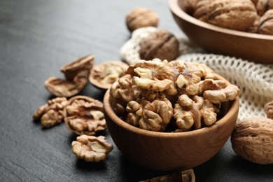 Photo of Fresh ripe walnuts and shells on black table, closeup. Space for text