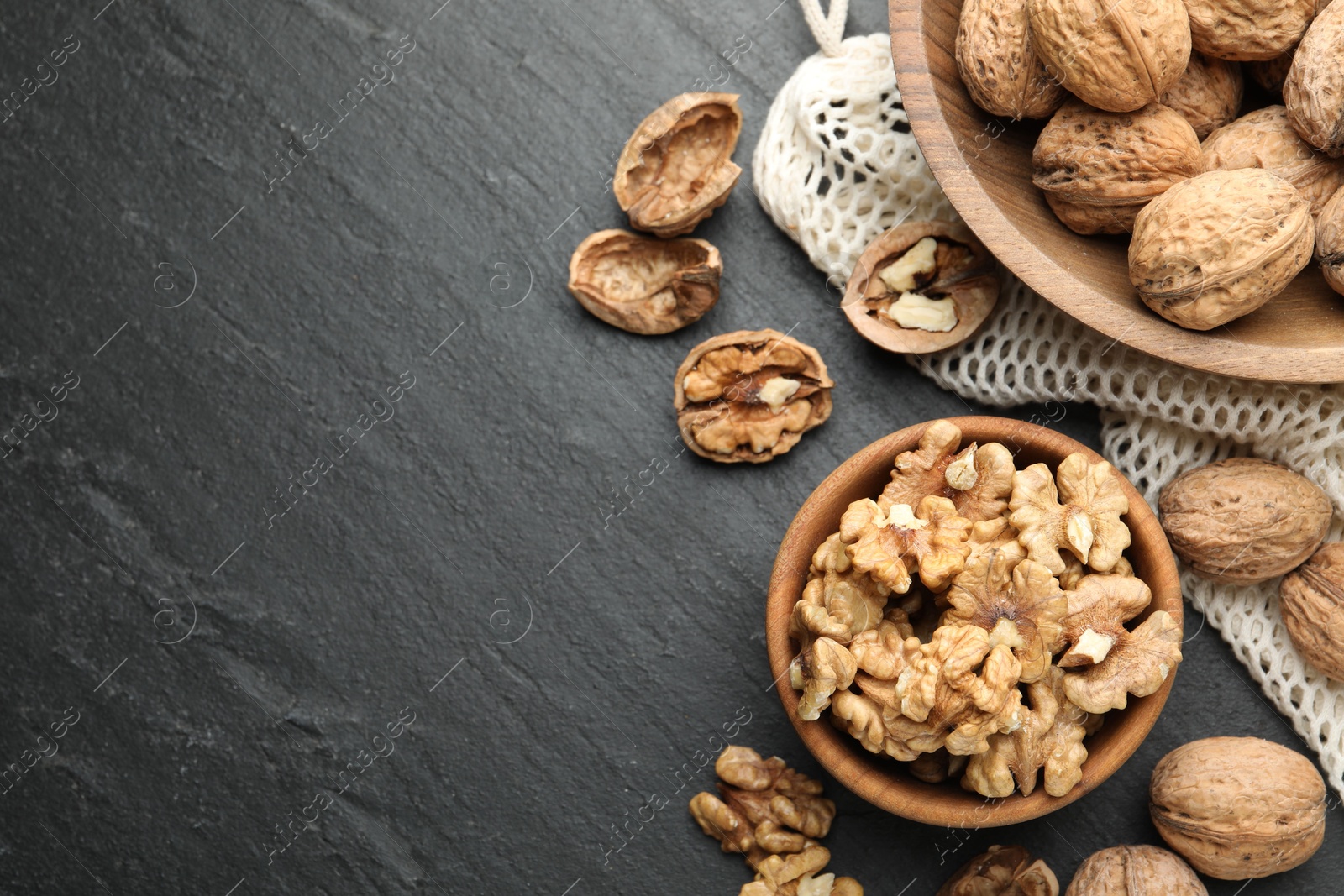 Photo of Fresh ripe walnuts and shells on black table, flat lay. Space for text