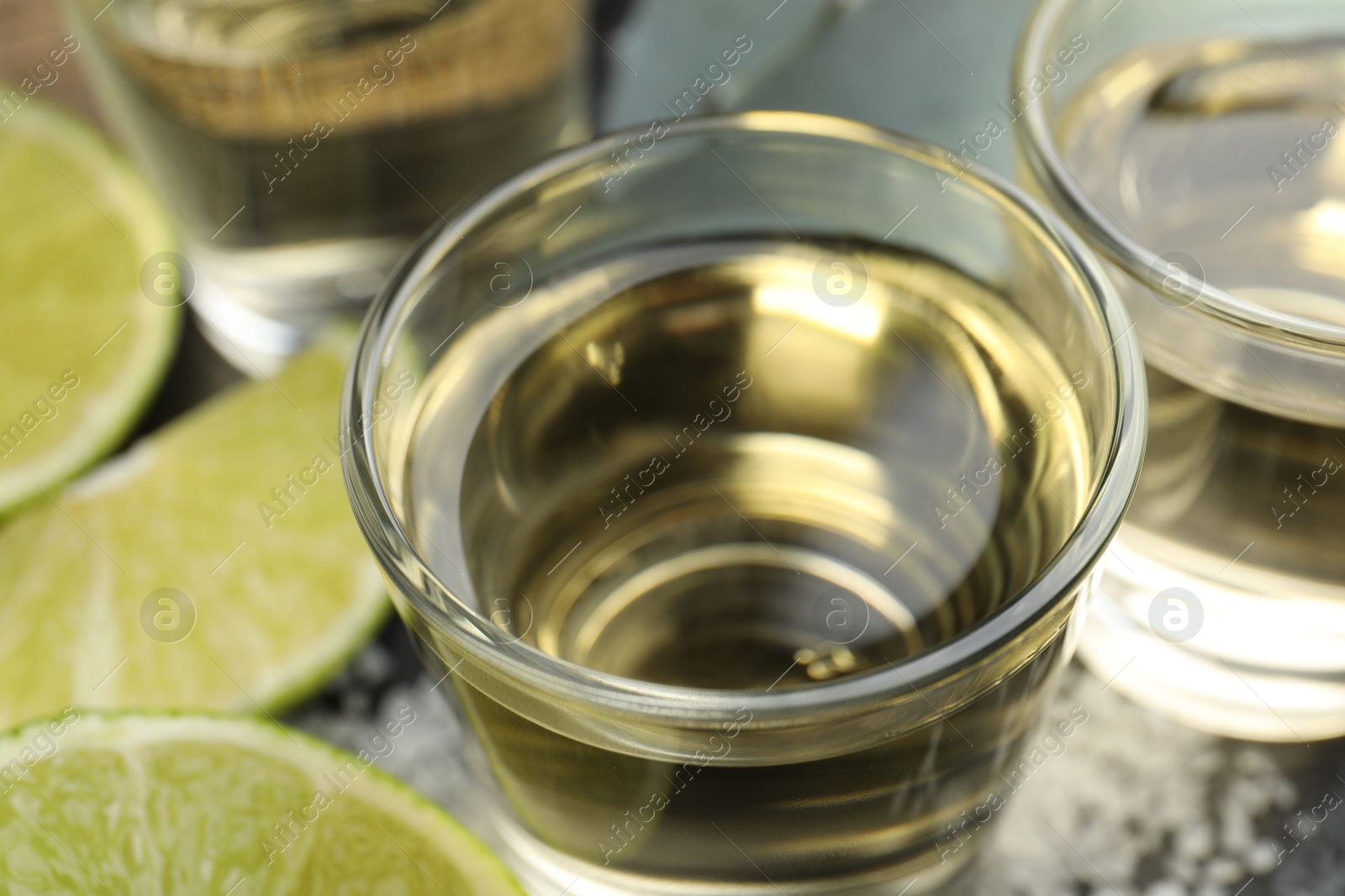 Photo of Mexican tequila shots and slices of lime on table, closeup