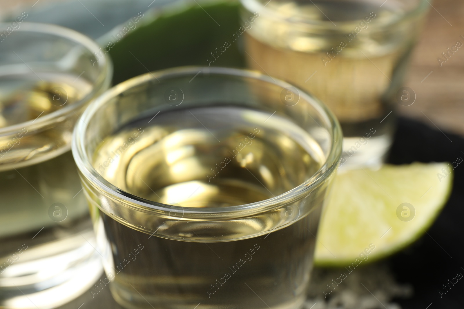 Photo of Mexican tequila shots and slice of lime on table, closeup