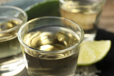 Photo of Mexican tequila shots and slice of lime on table, closeup