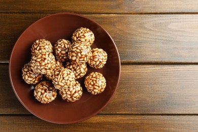 Photo of Delicious chocolate puffed rice balls in bowl on wooden table, top view. Space for text