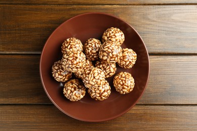 Photo of Delicious chocolate puffed rice balls in bowl on wooden table, top view