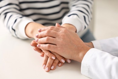 Photo of Doctor supporting patient during appointment in hospital, closeup of hands