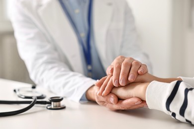 Photo of Doctor supporting patient during appointment in hospital, closeup of hands