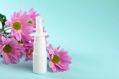 Photo of Allergy treatment. Nasal spray and flowers on light blue background. Space for text