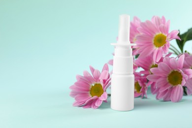 Photo of Allergy treatment. Nasal spray and flowers on light blue background. Space for text