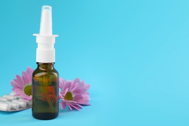 Photo of Allergy treatment. Nasal spray, pills and flowers on light blue background. Space for text