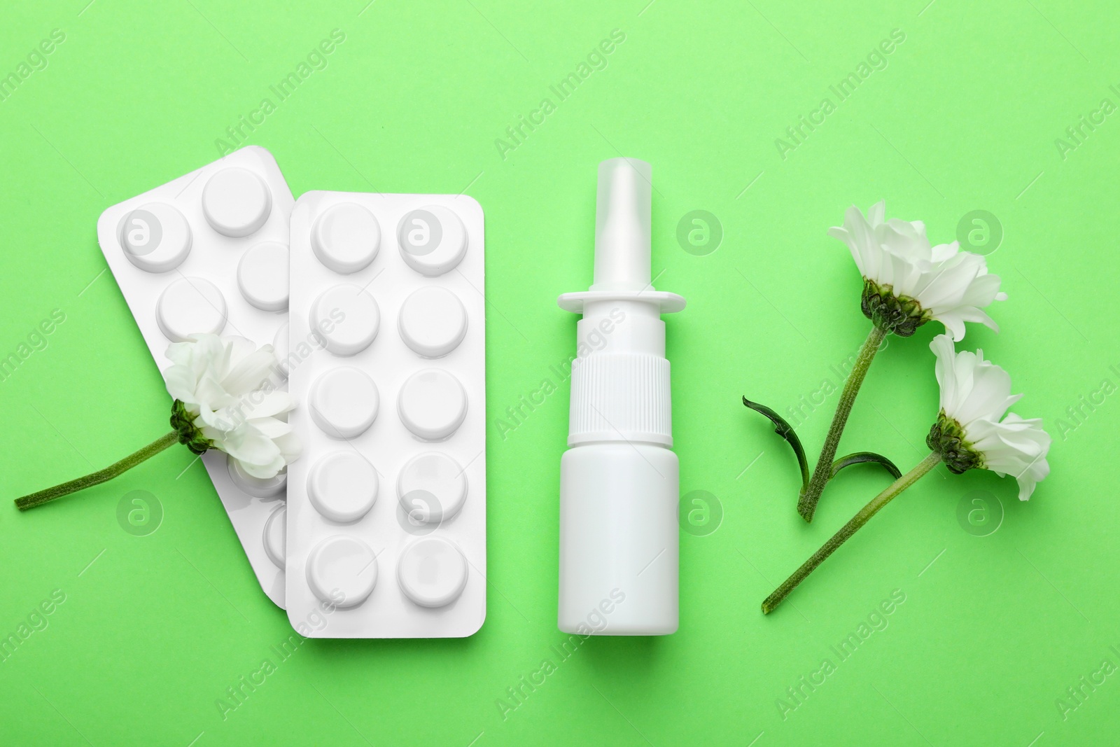 Photo of Allergy treatment. Nasal spray, pills and flowers on green background, flat lay