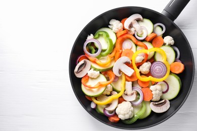 Photo of Frying pan with mix of vegetables and mushrooms on white wooden table, top view. Space for text