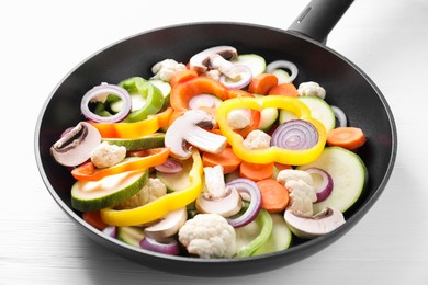 Photo of Frying pan with mix of vegetables and mushrooms on white wooden table, closeup