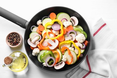 Photo of Frying pan with mix of vegetables, mushrooms and spices on white wooden table, top view