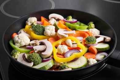 Photo of Frying pan with mix of vegetables and mushrooms on cooktop, closeup