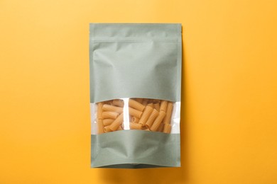 Photo of Paper pouch bag with pasta on yellow background, top view