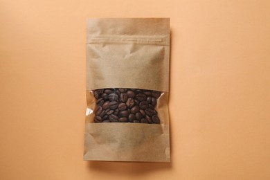 Photo of Paper pouch bag with coffee beans on color background, top view