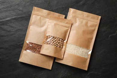 Photo of Paper pouch bags with different products on black table, top view