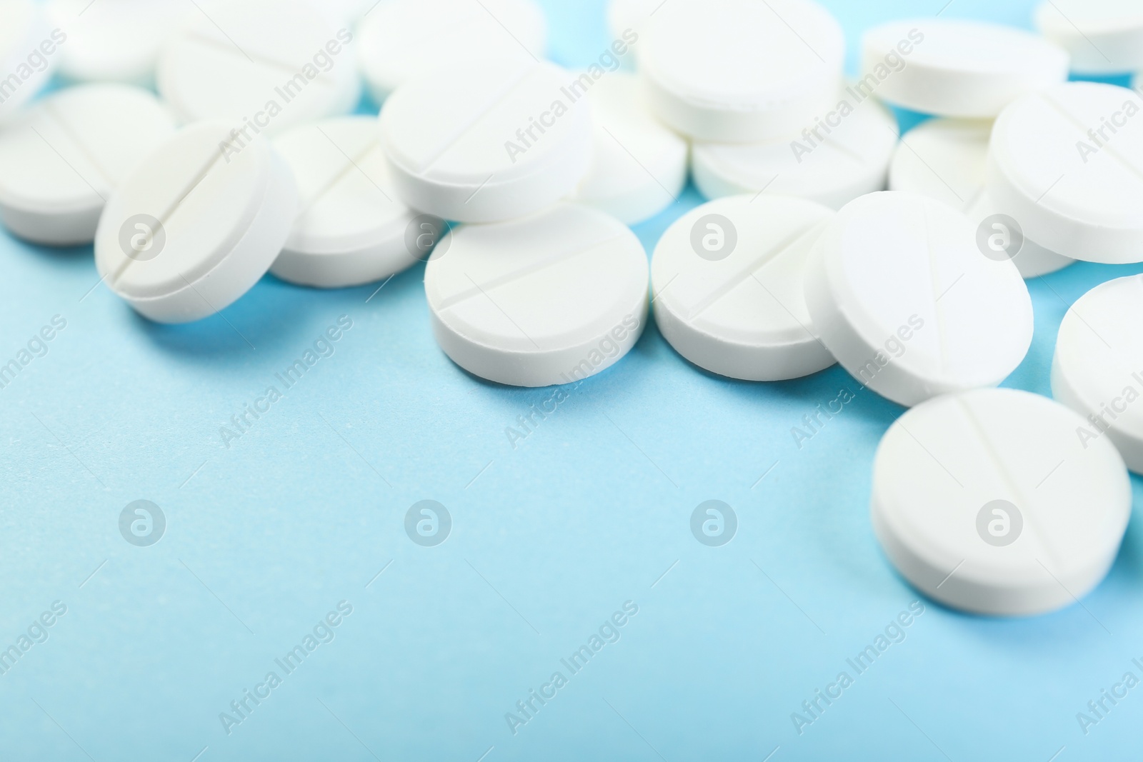 Photo of Many antibiotic pills on light blue background, closeup. Space for text