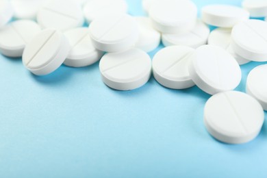 Photo of Many antibiotic pills on light blue background, closeup. Space for text