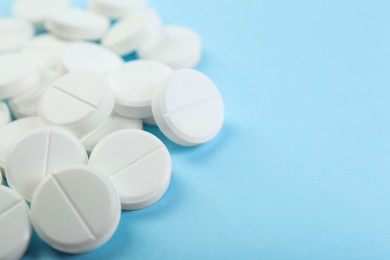 Photo of Many antibiotic pills on light blue background, closeup. Space for text