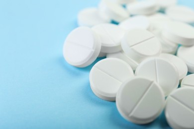 Photo of Many antibiotic pills on light blue background, closeup. Space for text