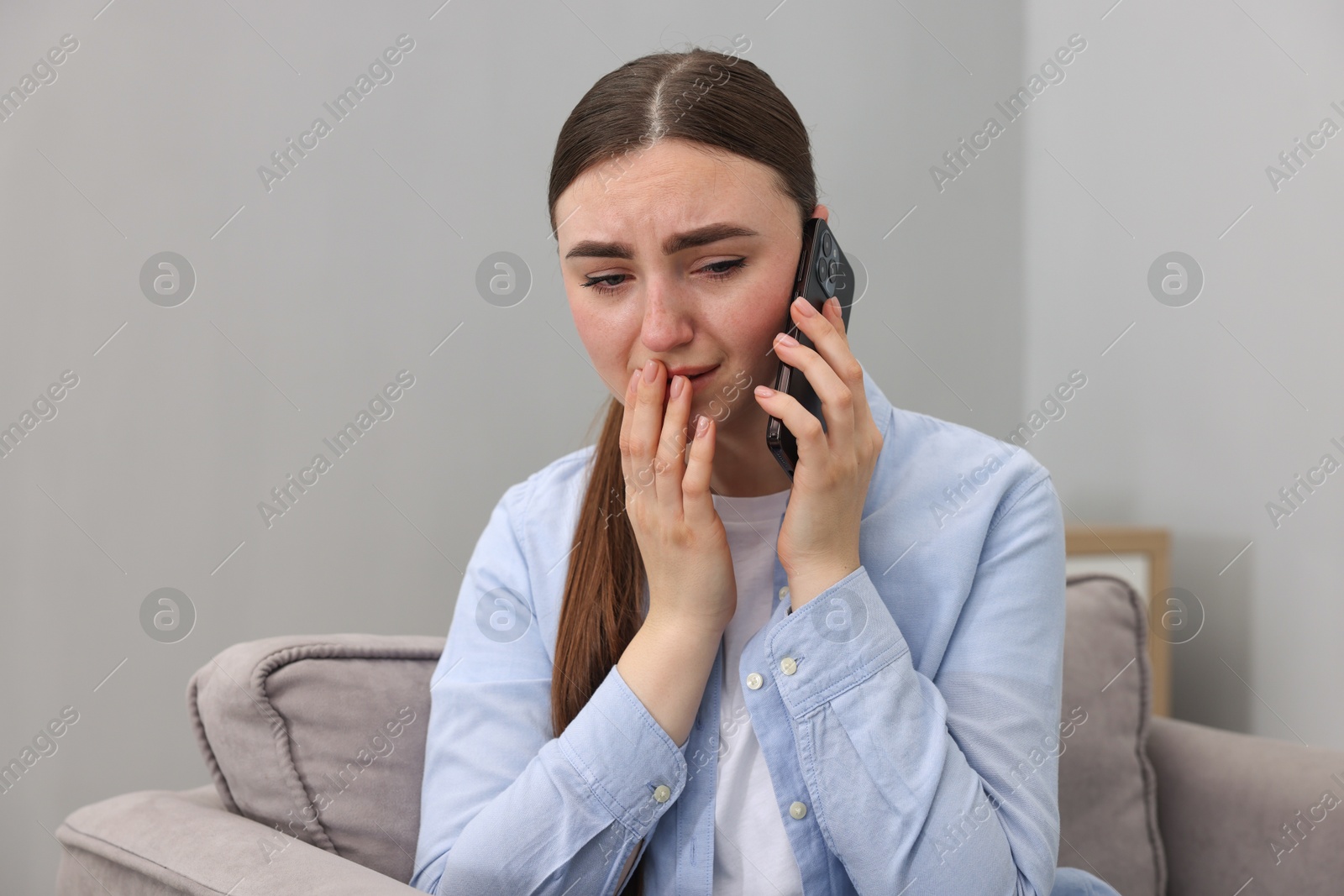 Photo of Stressed woman calling hotline for mental health help in armchair at home