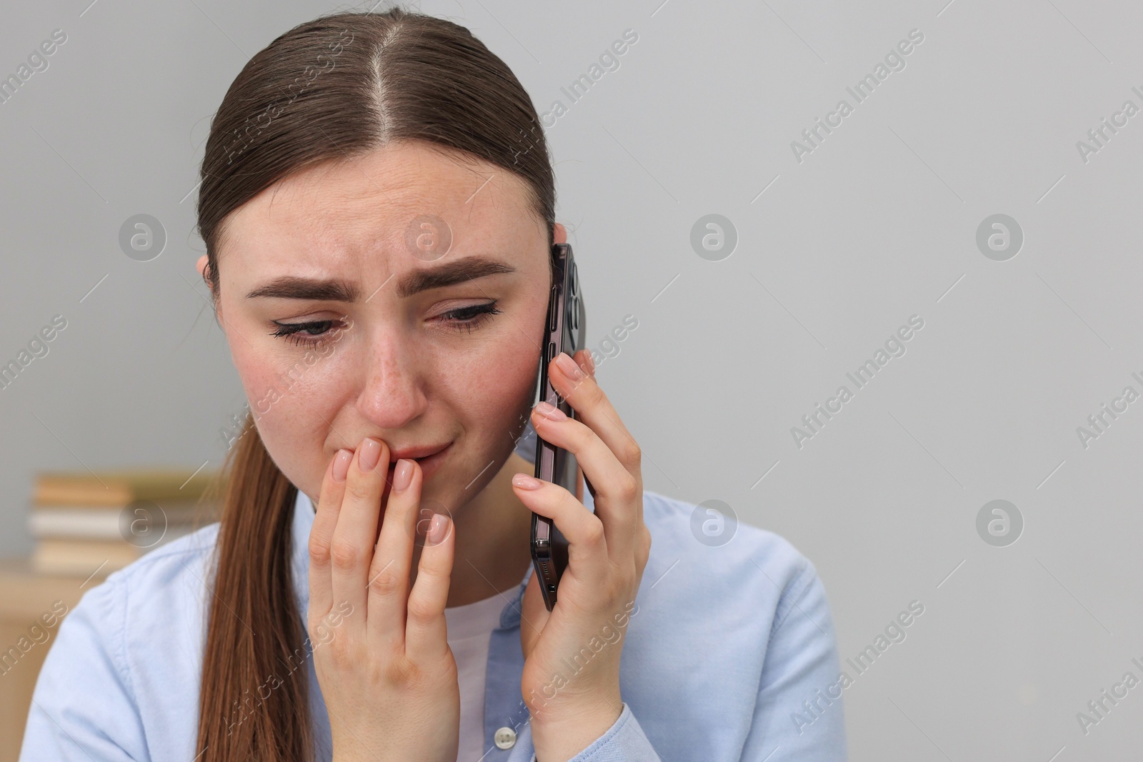 Photo of Stressed woman calling hotline for mental health help on grey background. Space for text