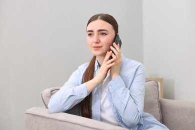 Photo of Stressed woman calling hotline for mental health help in armchair at home