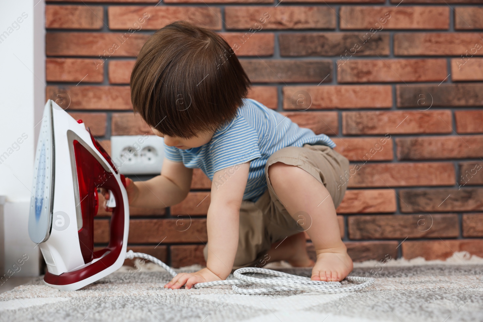 Photo of Little boy playing with iron at home. Child in danger