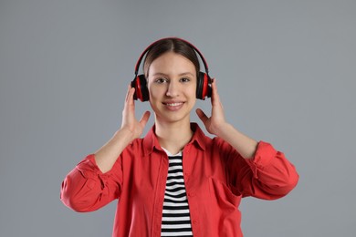 Photo of Portrait of smiling teenage girl in headphones listening to music on grey background