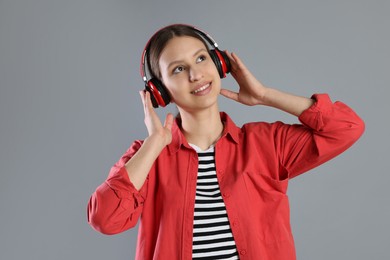 Photo of Portrait of smiling teenage girl in headphones listening to music on grey background