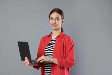 Photo of Portrait of smiling teenage girl with laptop on grey background