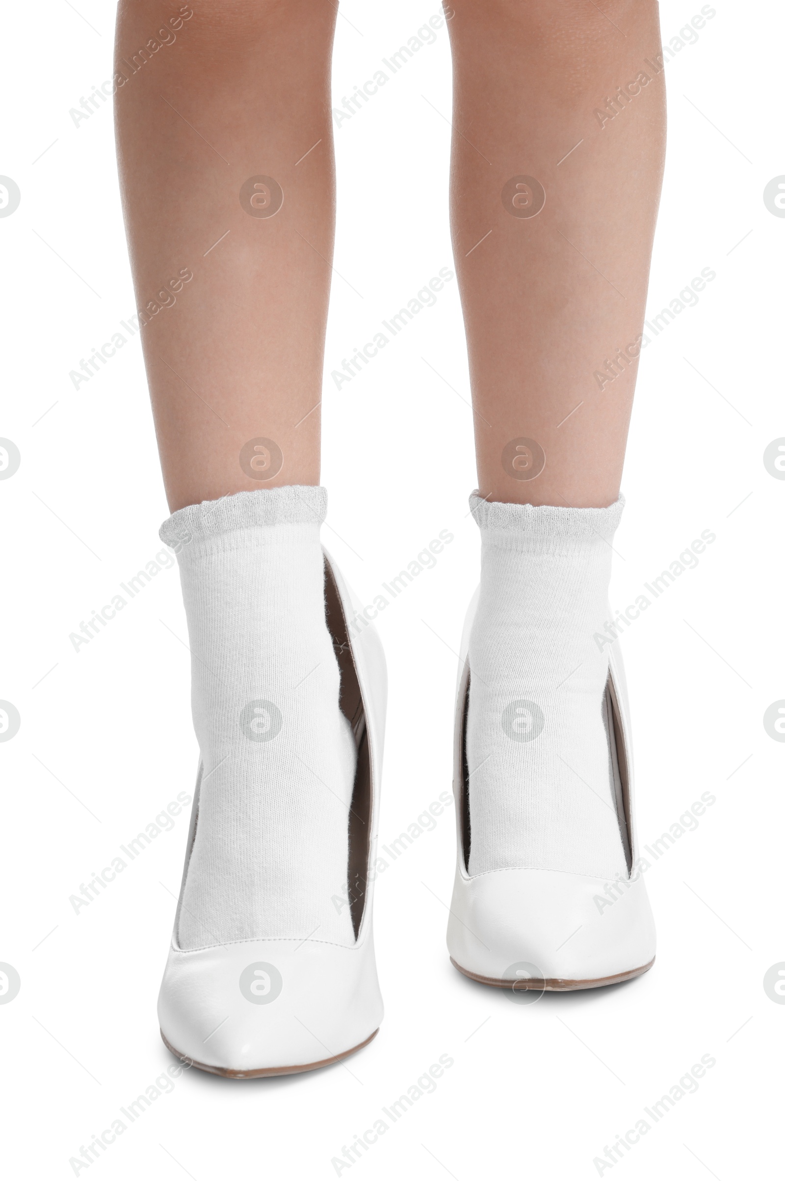 Photo of Little girl wearing oversized high heeled shoes on white background, closeup