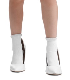 Photo of Little girl wearing oversized high heeled shoes on white background, closeup