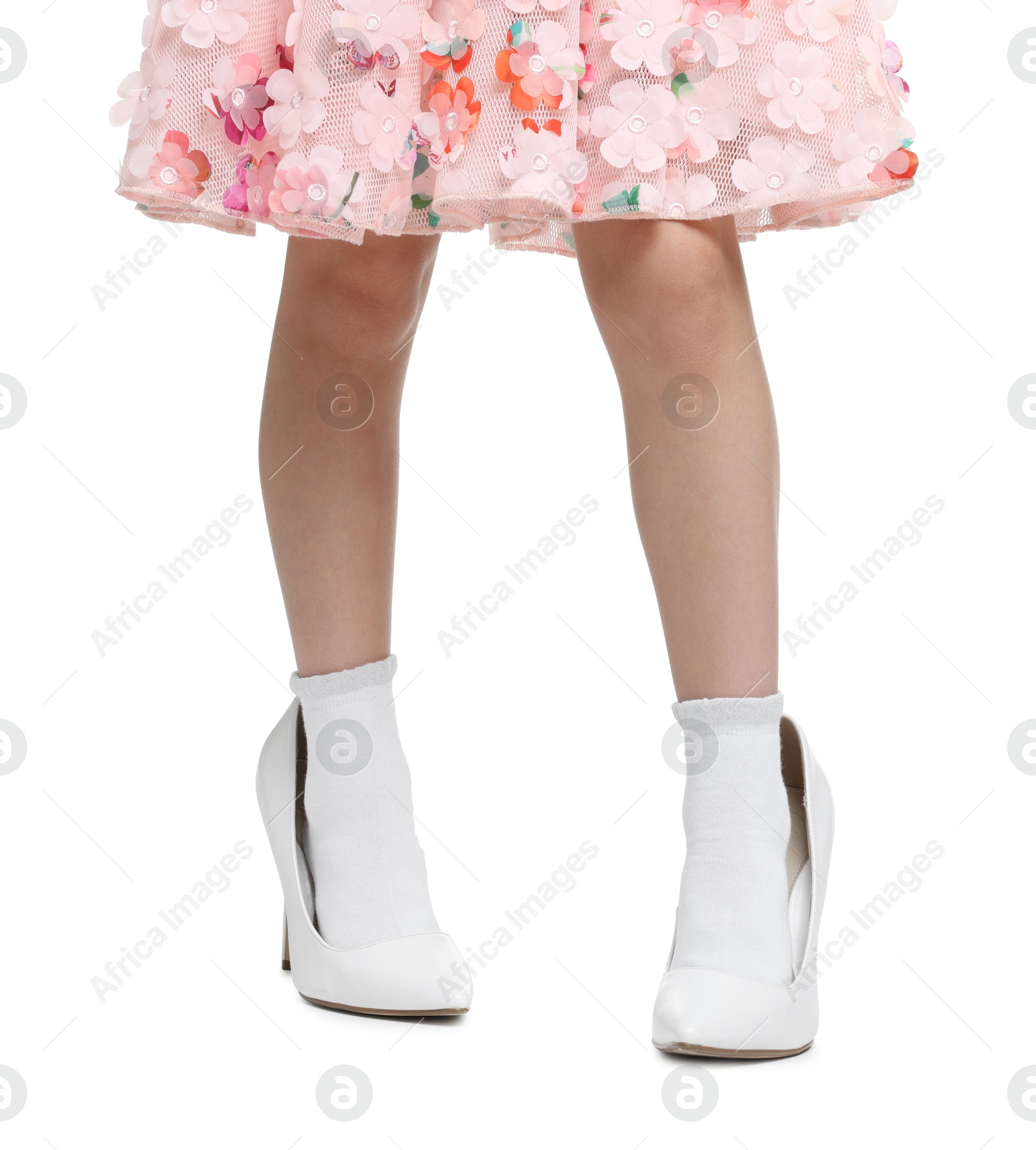 Photo of Little girl wearing oversized high heeled shoes on white background, closeup