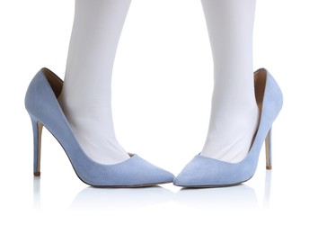 Photo of Little girl wearing oversized high heeled shoes on white background, closeup