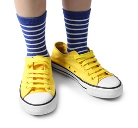 Photo of Child wearing oversized yellow sneakers on white background, closeup