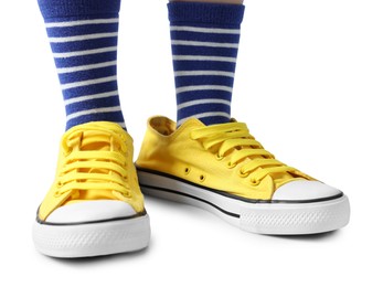 Photo of Child wearing oversized yellow sneakers on white background, closeup