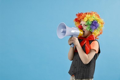 Photo of Little boy dressed like clown shouting in megaphone on light blue background, space for text. Surprise party