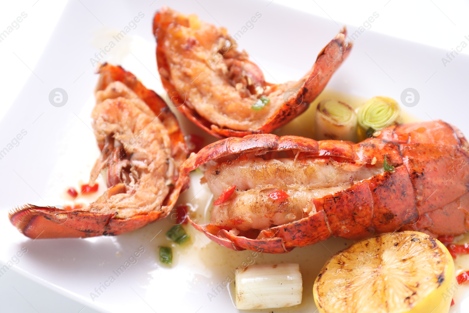 Photo of Delicious lobster tails with lemon and green onion on white table, above view