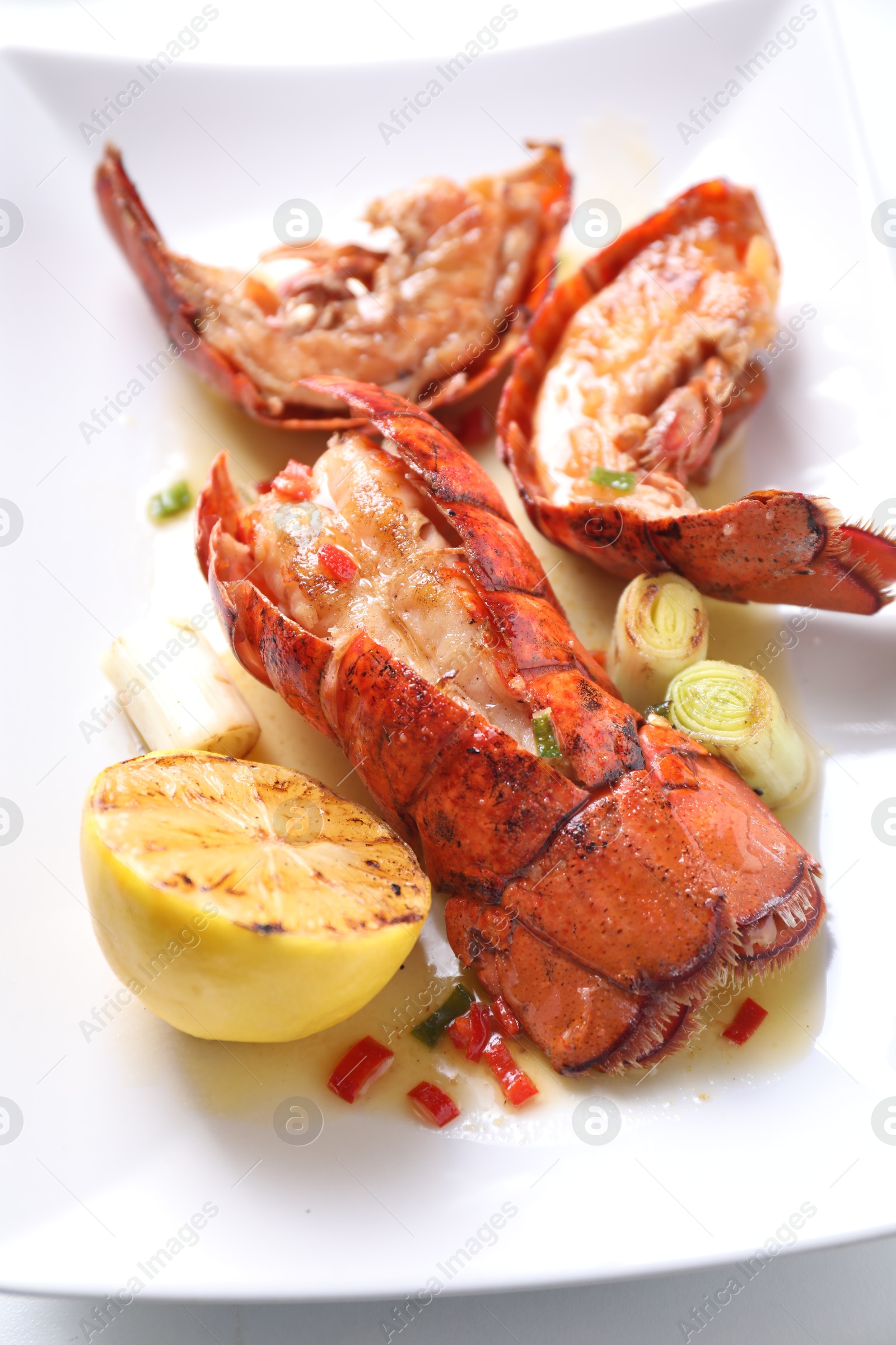 Photo of Delicious lobster tails with lemon and green onion on white table, above view