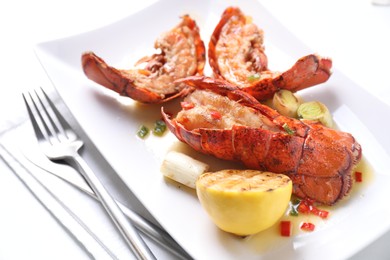 Photo of Delicious lobster tails with lemon and green onion on white table, closeup