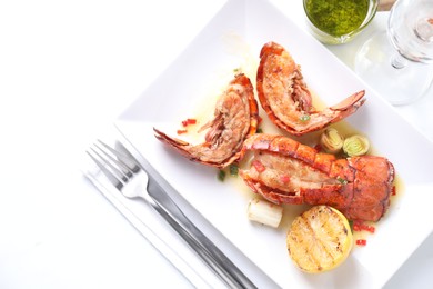 Photo of Delicious lobster tails with lemon and green onion on white table, flat lay. Space for text