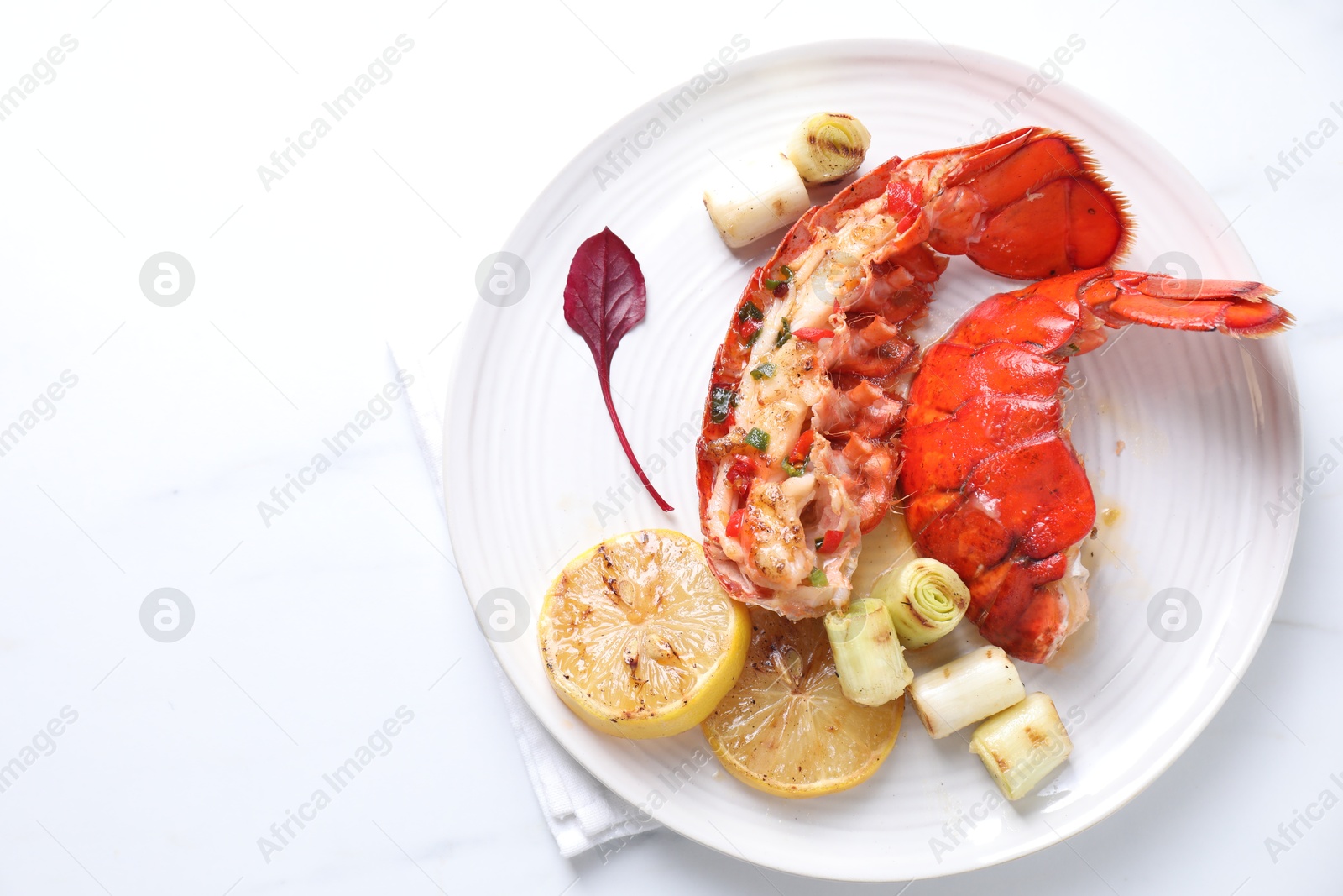 Photo of Delicious lobster tails with lemon and green onion on white table, top view. Space for text