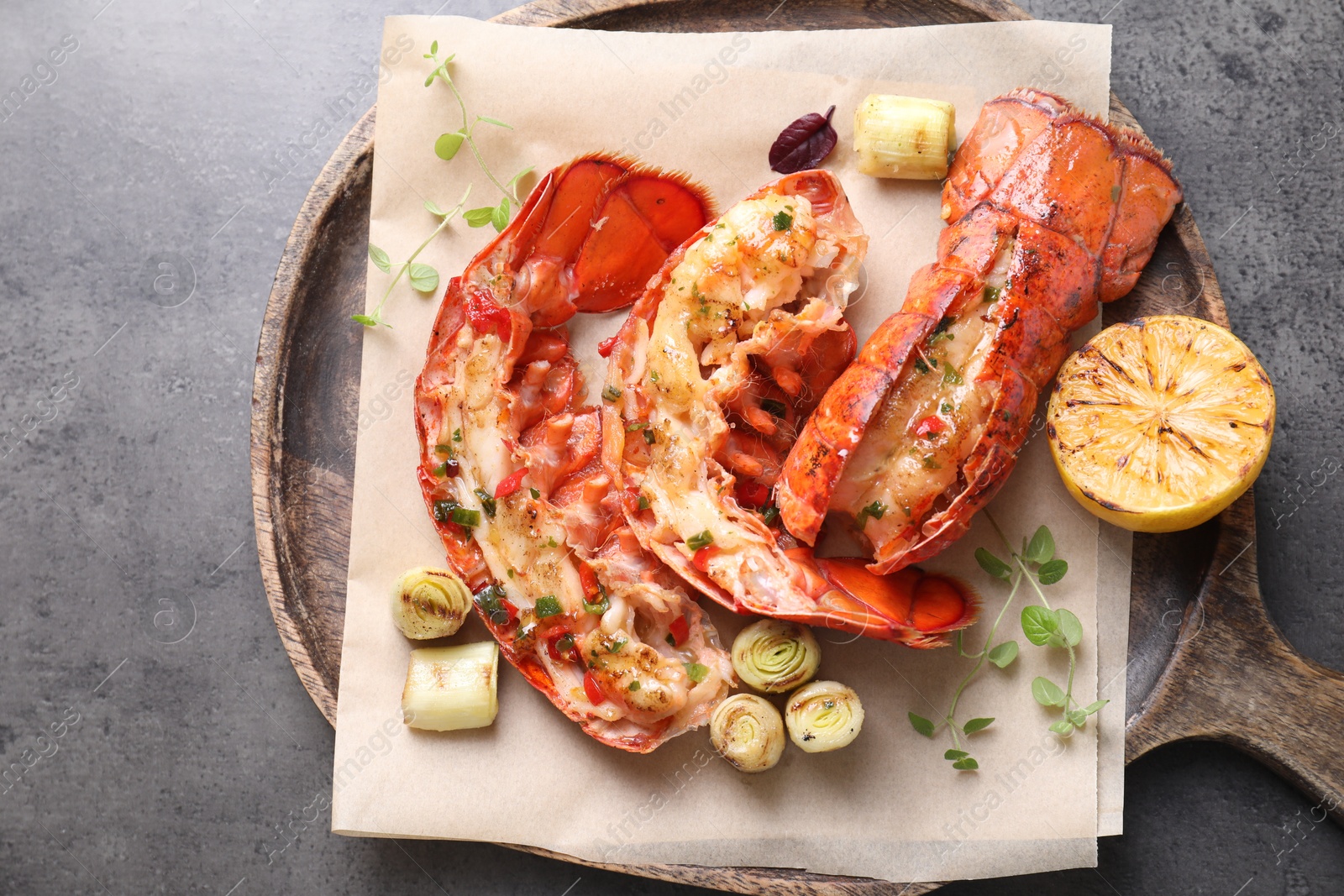 Photo of Delicious lobster tails with lemon, microgreens and green onion on grey textured table, top view