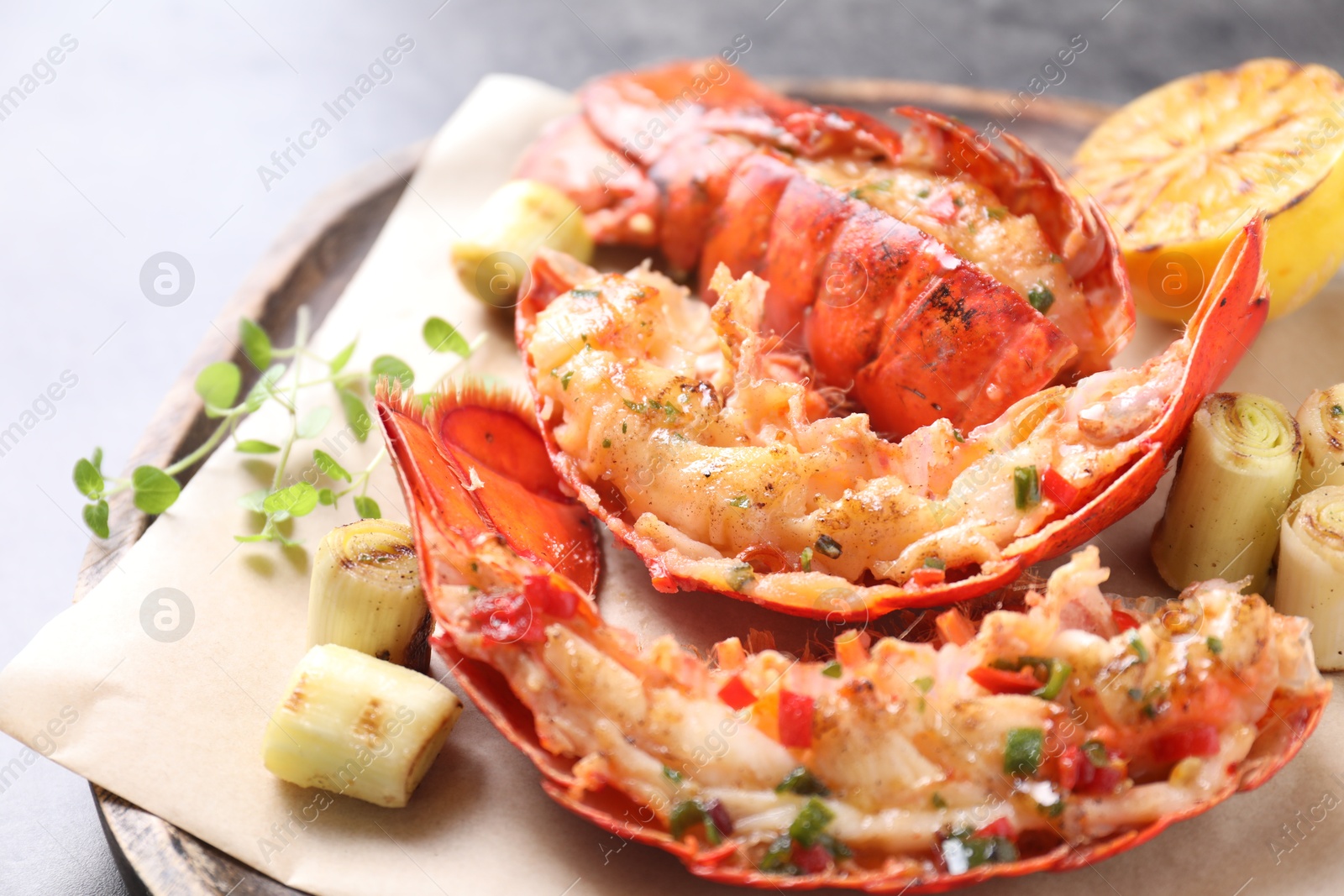 Photo of Delicious lobster tails with lemon, microgreens and green onion on grey table, closeup