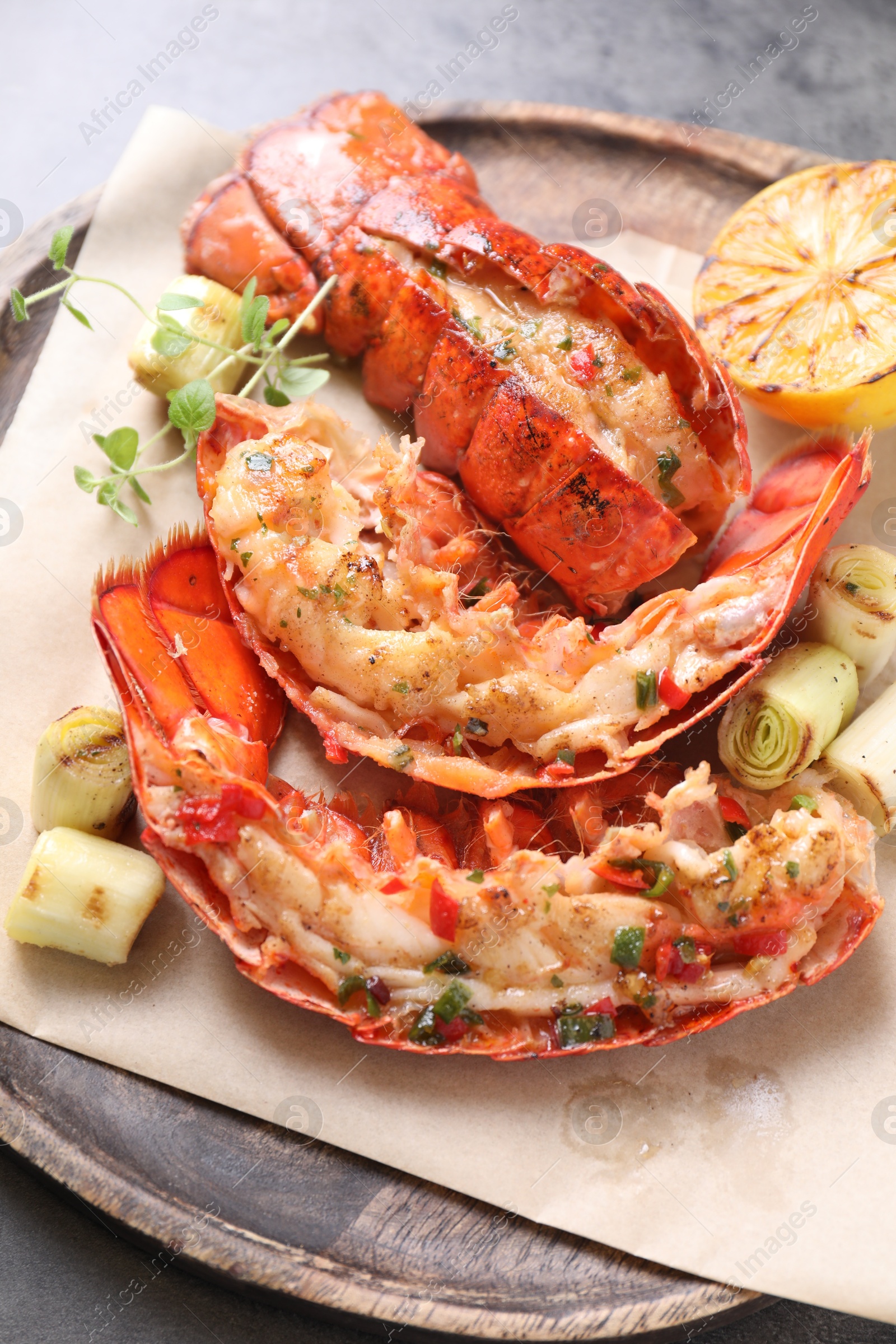 Photo of Delicious lobster tails with lemon, microgreens and green onion on grey textured table, above view