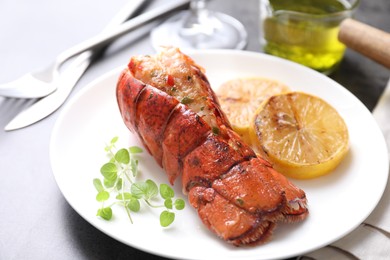 Photo of Delicious lobster tail with microgreens and slices of lemon on grey table, closeup