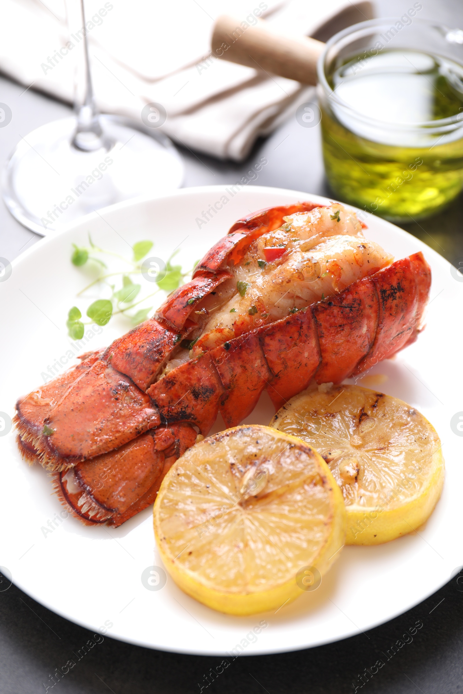 Photo of Delicious lobster tail with microgreens and slices of lemon on grey table, closeup