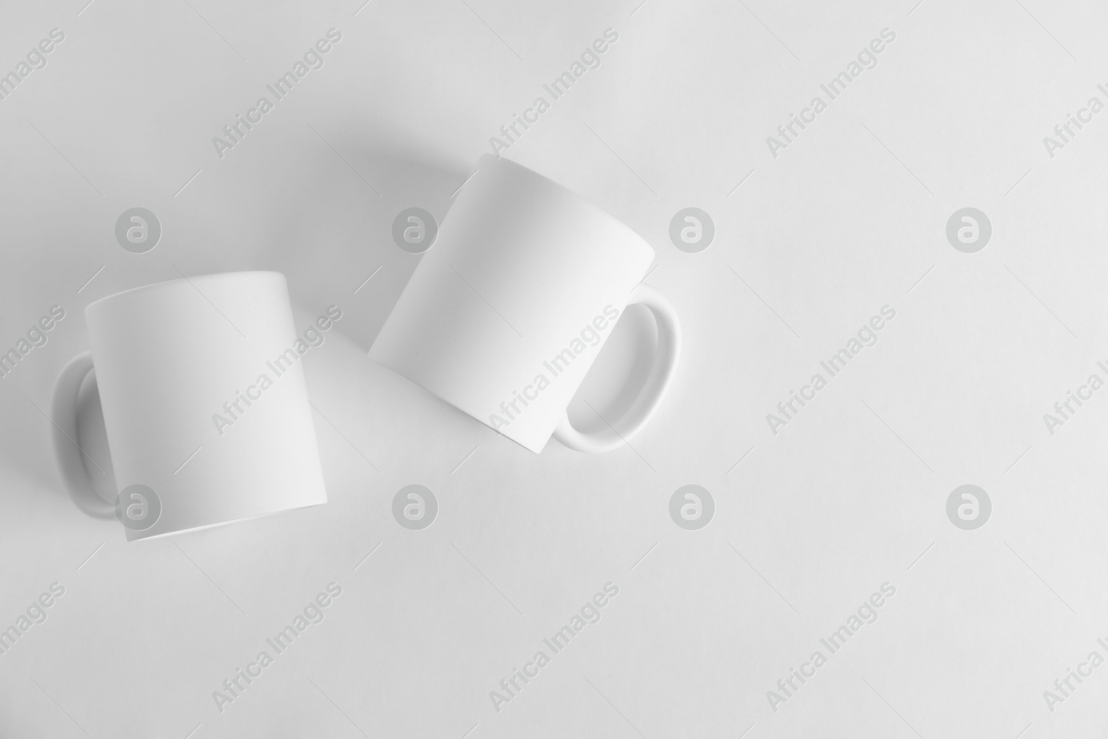 Photo of Two blank mugs on white background, top view. Mockup for design