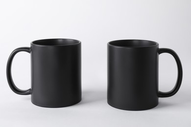 Photo of Two blank black mugs on white background. Mockup for design